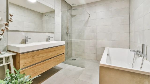 Ein modernes Badezimmer mit einer ebenerdigen,  barrierefreien Dusche und Fliesen in Naturtönen.