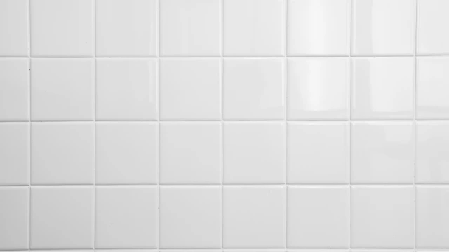 Eine Wand mit quadratischen, weißen Fliesen und sauberen Fugen.