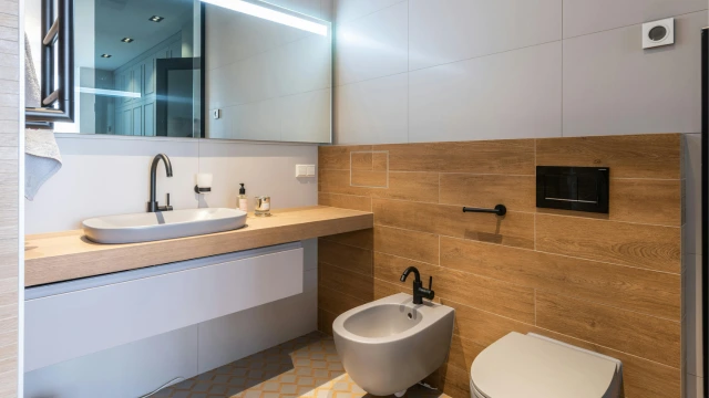 Ein modernes Badezimmer mit XXL-Fliesen, einem Spiegel mit Beleuchtung und einem Hänge-WC.