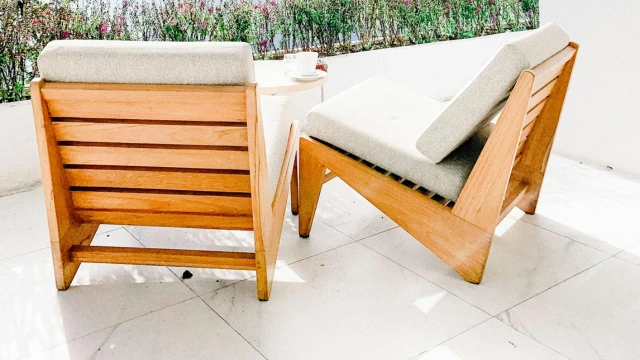 Eine Terasse mit großen, hellen Terassenfliesen und Holzmöbeln.